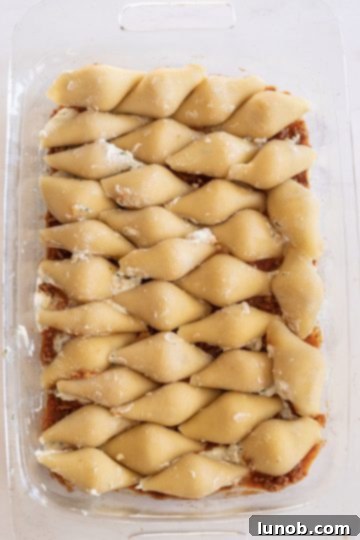 Pyrex baking dish with a layer of sauce and stuffed shells arranged inside.