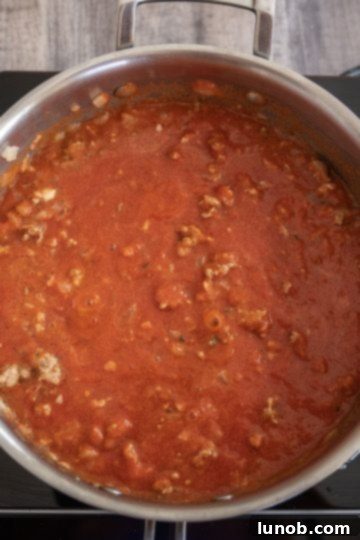 Red tomato sauce added to browned sausage and onions