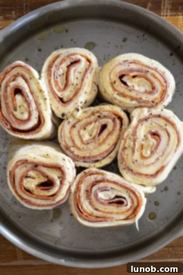 The rolled pepperoni stromboli, cut into eight equal pinwheels and arranged in a round baking pan, touching in the middle with space around the edges