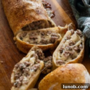 A freshly baked Italian sausage bread loaf, sliced open to reveal its savory sausage and melted cheese filling.