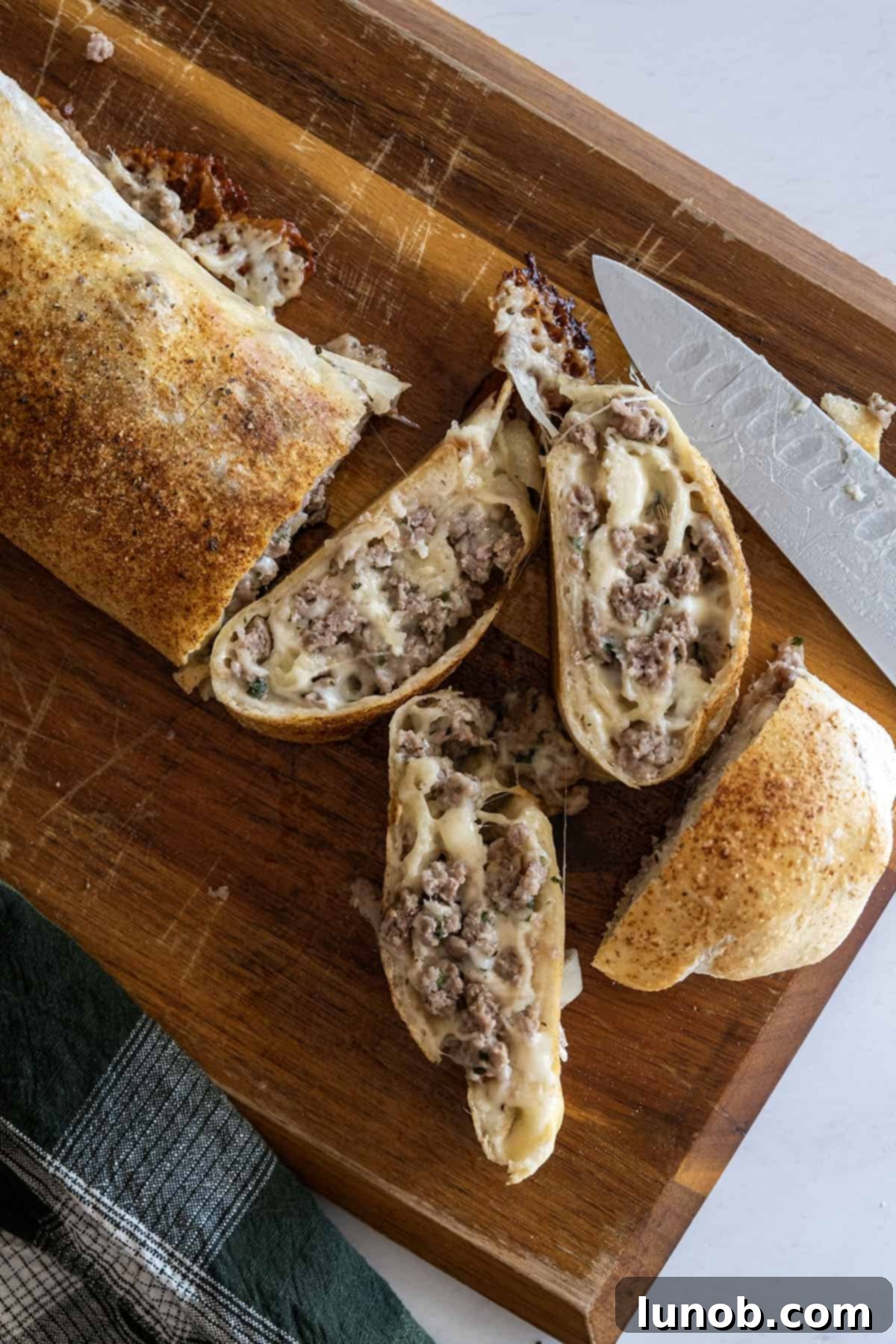 A freshly baked Italian sausage bread loaf, golden brown and sliced open, revealing its rich, savory interior of sausage and melted cheese.