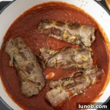 Braciole added to the simmering tomato sauce, partially covered