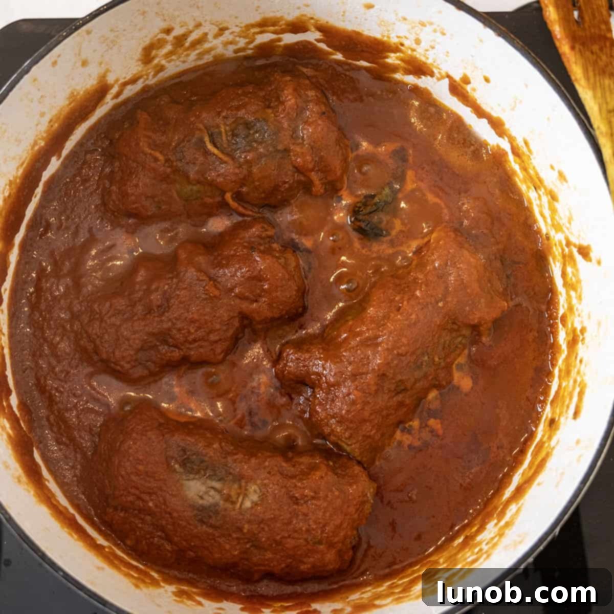 Braised braciole simmering in rich tomato sauce