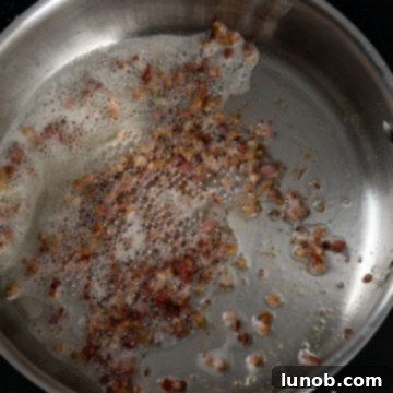 Frying pancetta sizzling in a hot pan, turning golden