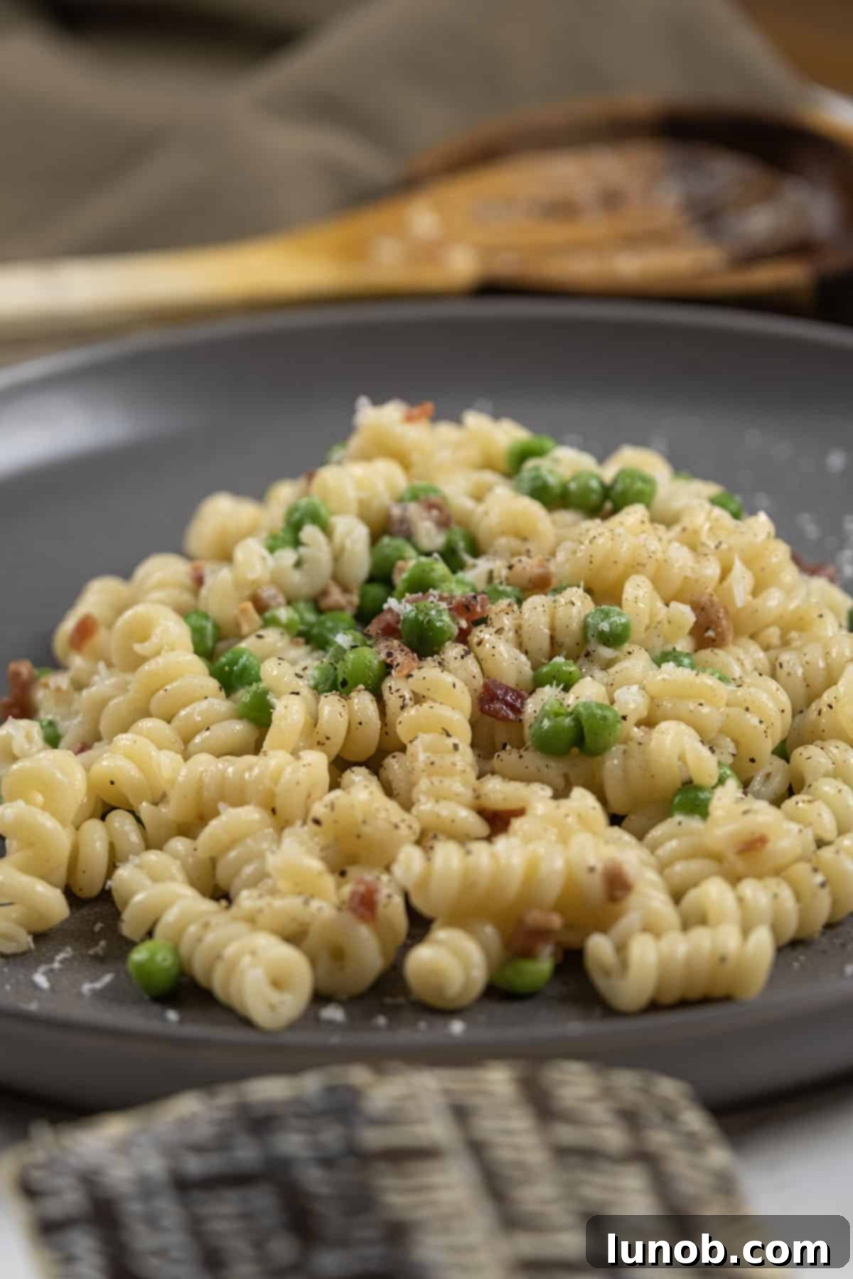 A close-up shot of creamy pasta with peas and pancetta, perfectly plated and ready to eat.