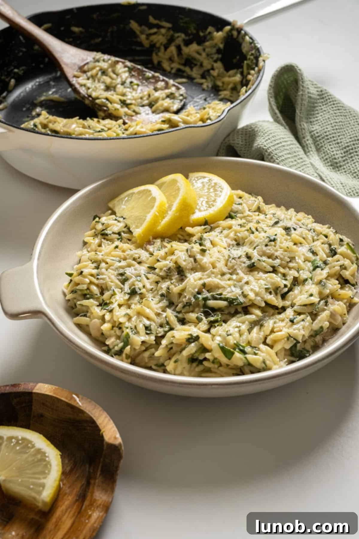 Bright Lemon Spinach Orzo 2 A bowl of creamy lemon spinach orzo pasta, garnished with fresh lemon slices and a sprinkle of chopped parsley.