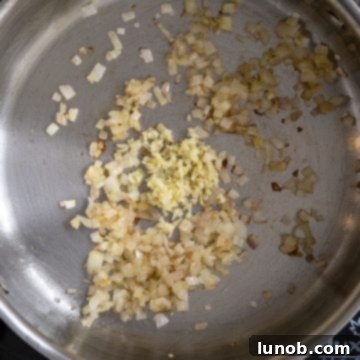 Bright Lemon Spinach Orzo 4 Close-up of minced shallots and garlic sautéing in olive oil in a pan.