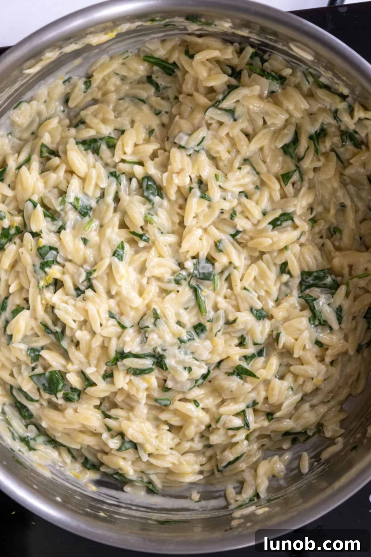Bright Lemon Spinach Orzo 6 Heavy cream and parmesan being stirred into the lemon spinach orzo, making it creamy.