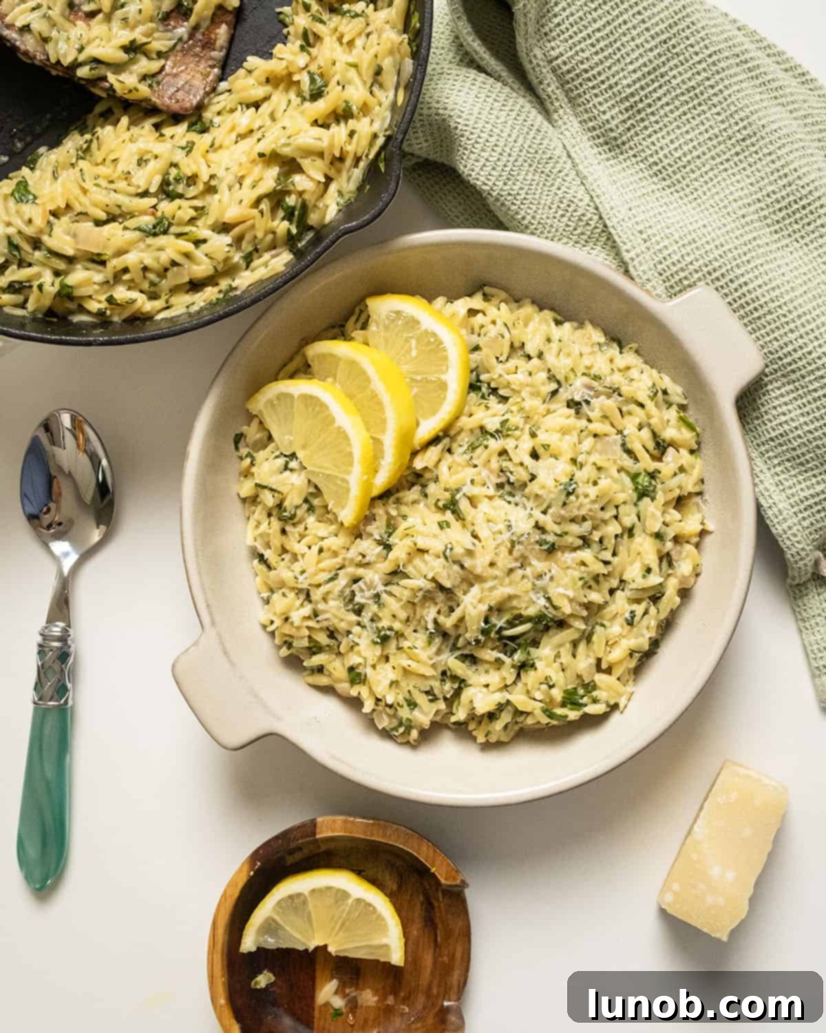 Bright Lemon Spinach Orzo 7 Close-up of a serving of lemon spinach orzo in a white bowl, garnished with lemon slices.