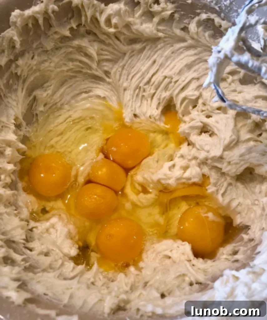 Cheesecake Perfection 8 Adding eggs one by one to the cheesecake filling.