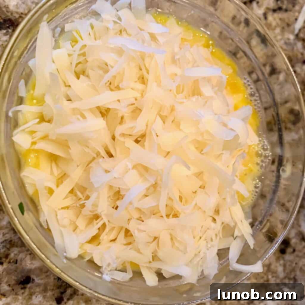 Close-up of the egg and Parmigiano cheese mixture being incorporated into the Italian Wedding Soup, a traditional step for enhanced flavor and texture.