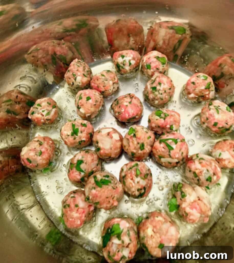 Gently stirring golden-brown meatballs in the Instant Pot, ensuring even browning before adding the broth for the Italian Wedding Soup.