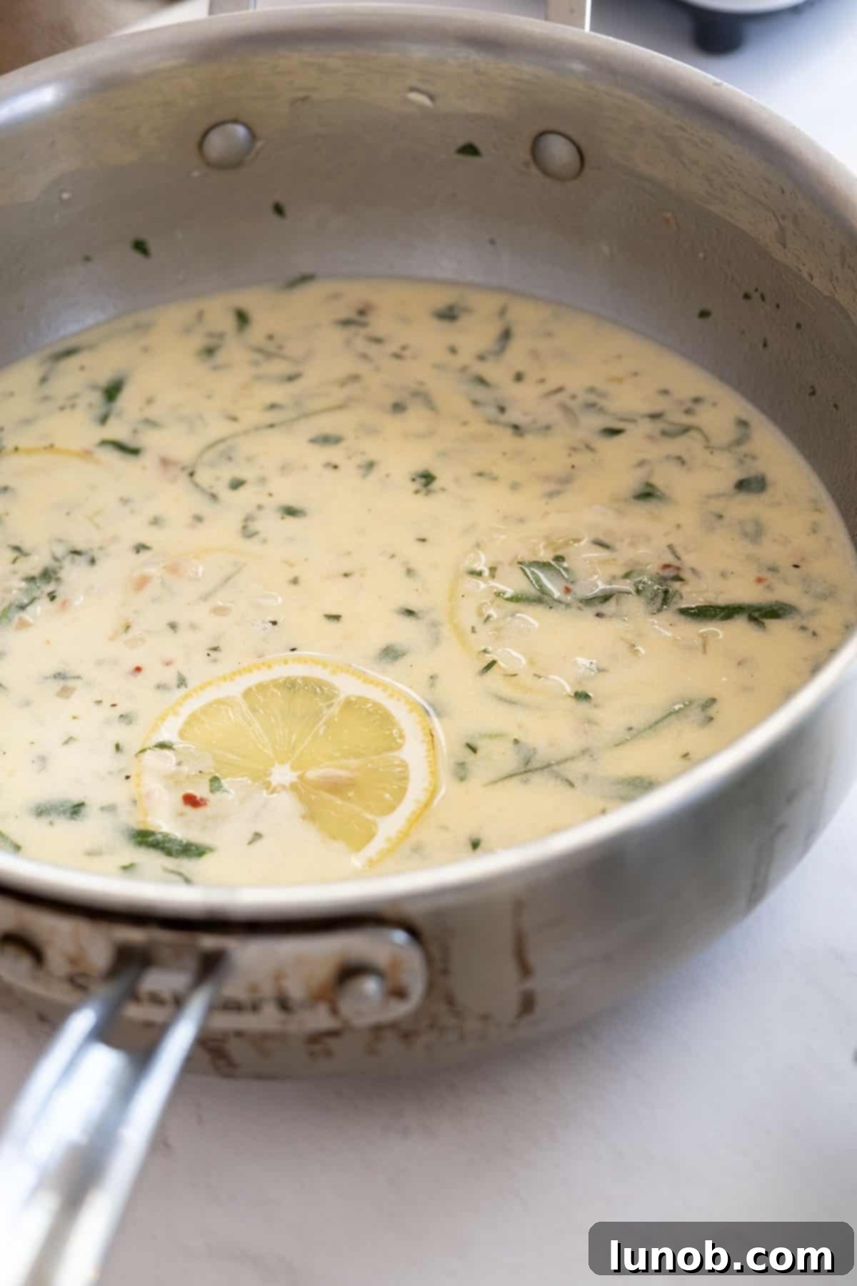 Velvety Lemon Sauce 10 A serving of creamy lemon sauce garnished with fresh herbs in a white bowl
