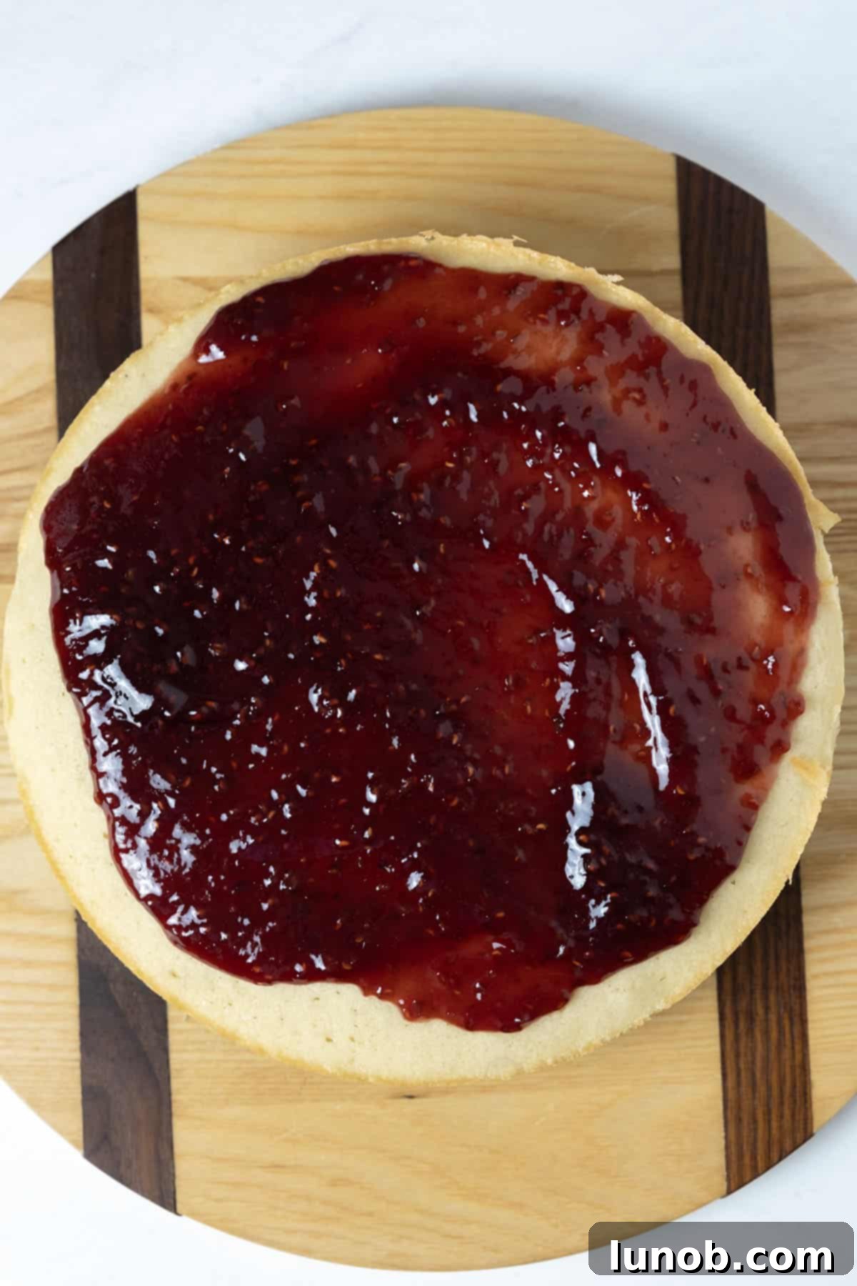Raspberry jam spread on the second white cake layer