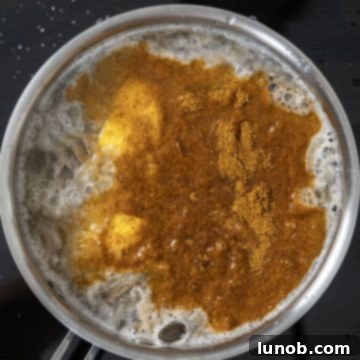 Seasonings, lemon, beer, and shrimp shells added to a large pot of boiling water, creating an aromatic stock.