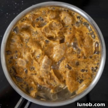 Shrimp stock boiling vigorously in a large pot, ready for the shrimp to be added.