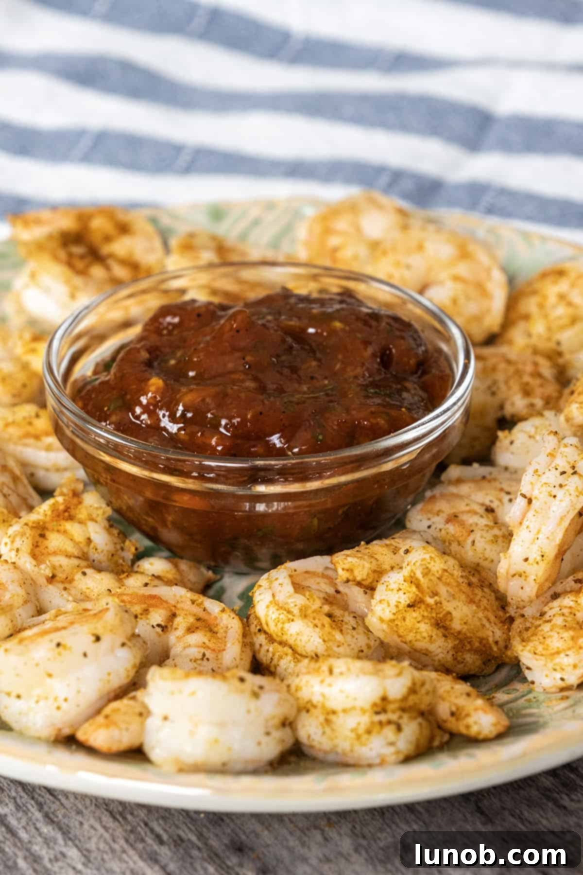 Beautifully arranged homemade shrimp cocktail with a bowl of spicy cocktail sauce and lemon slices.