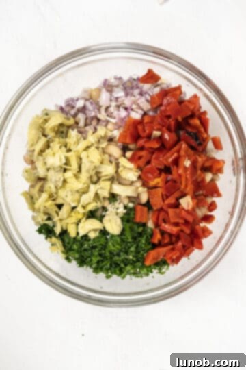 Mediterranean Farro White Bean Salad 5 A small bowl showing the dressing ingredients combined with roasted red pepper and artichoke hearts.