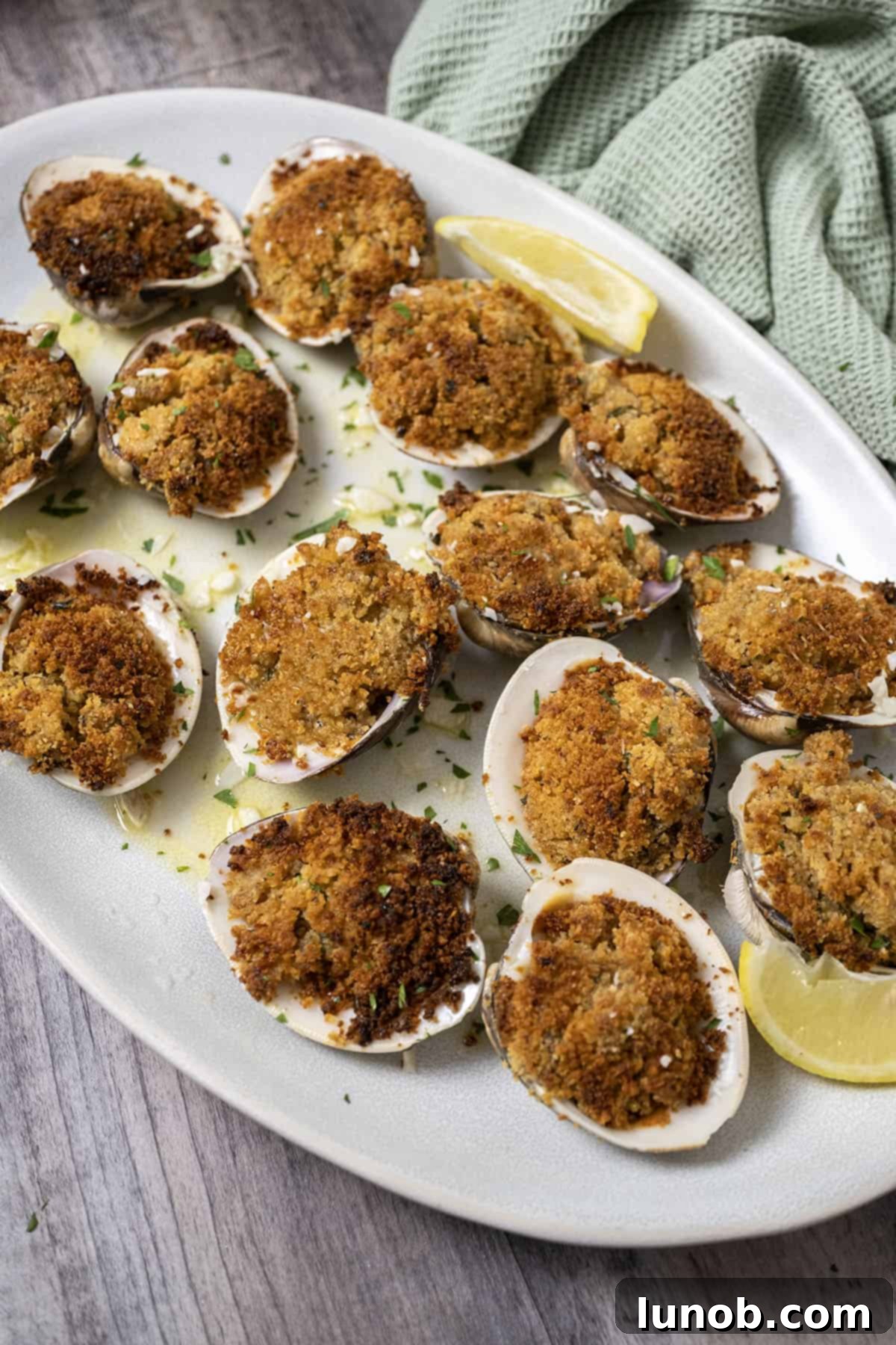 Classic Italian Stuffed Clams 9 Baked clams on a plate with lemon garlic sauce underneath.