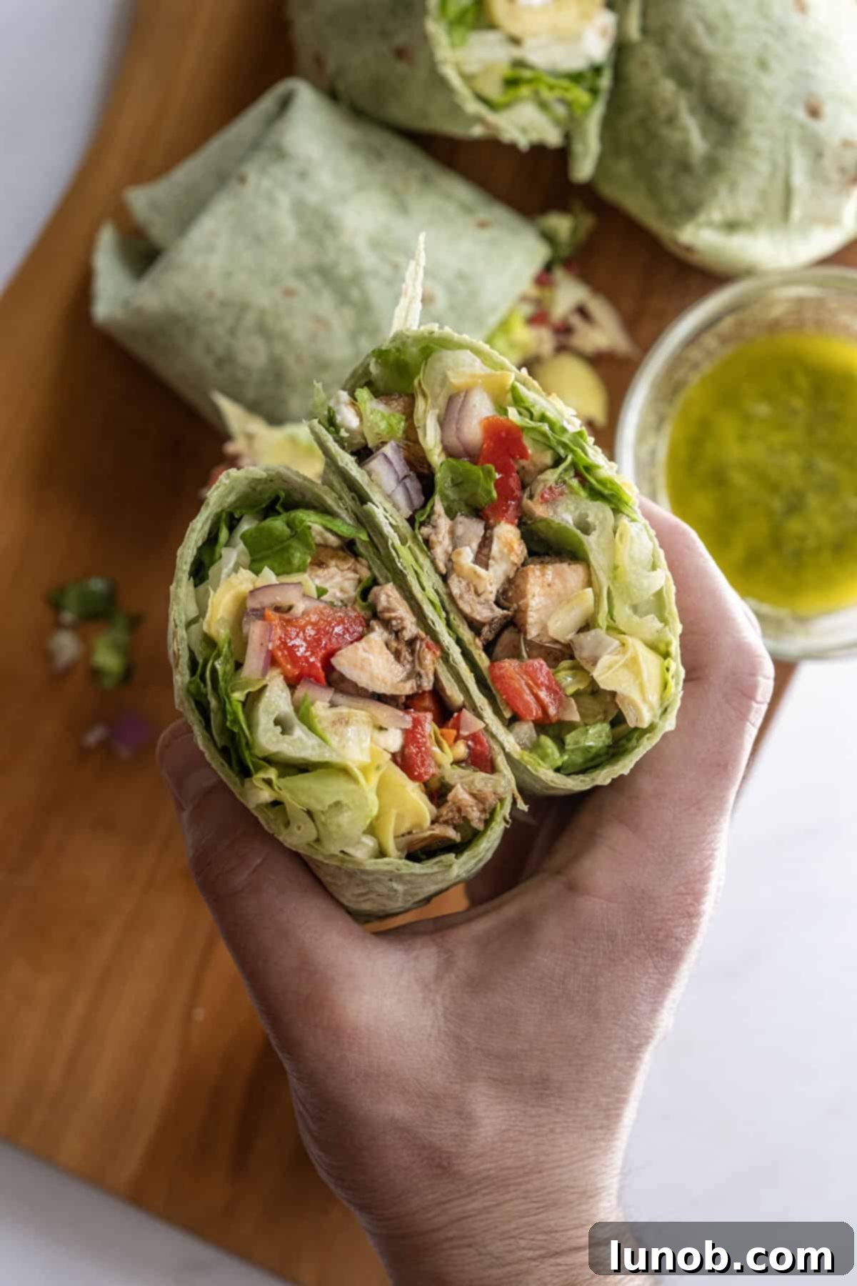 Zesty Mediterranean Chicken Pocket 2 Delicious Mediterranean chicken wrap, cut in half to show the filling of balsamic chicken, lettuce, roasted red peppers, and feta.