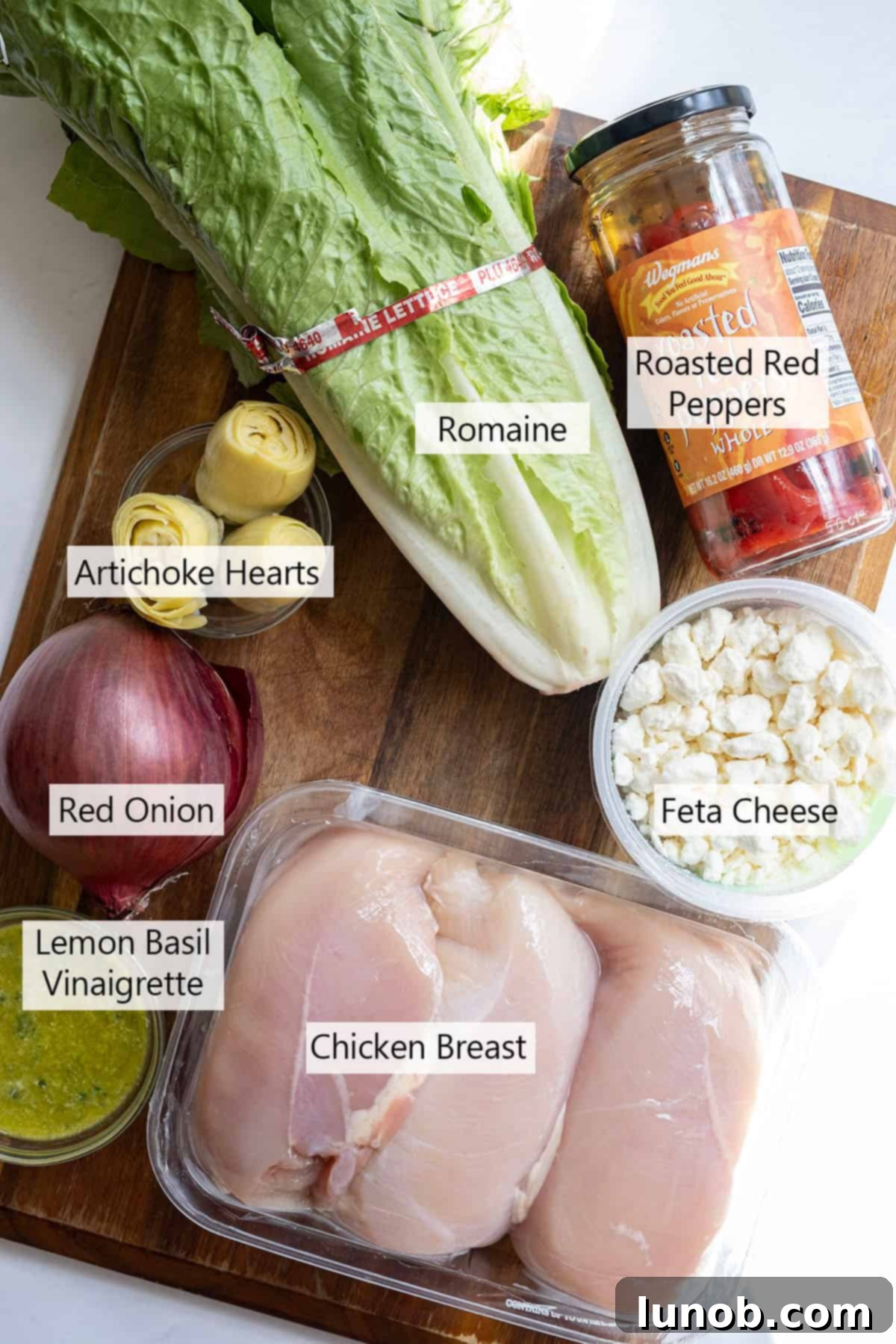 Zesty Mediterranean Chicken Pocket 3 Fresh ingredients laid out for Mediterranean chicken wraps, including chicken breasts, lettuce, red onion, roasted red peppers, and artichoke hearts, alongside olive oil, balsamic vinegar, and herbs.