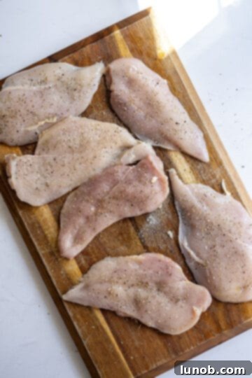 Zesty Mediterranean Chicken Pocket 5 Raw chicken breast seasoned with olive oil, oregano, salt, pepper, and garlic powder, ready for grilling.