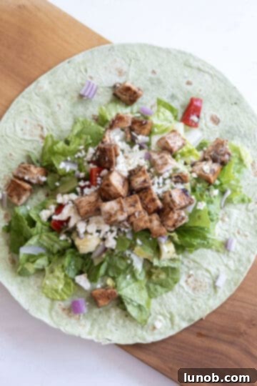 Zesty Mediterranean Chicken Pocket 9 A tortilla wrap completely filled with balsamic chicken, feta cheese, romaine lettuce, roasted red peppers, artichoke hearts, and red onion, ready to be rolled.