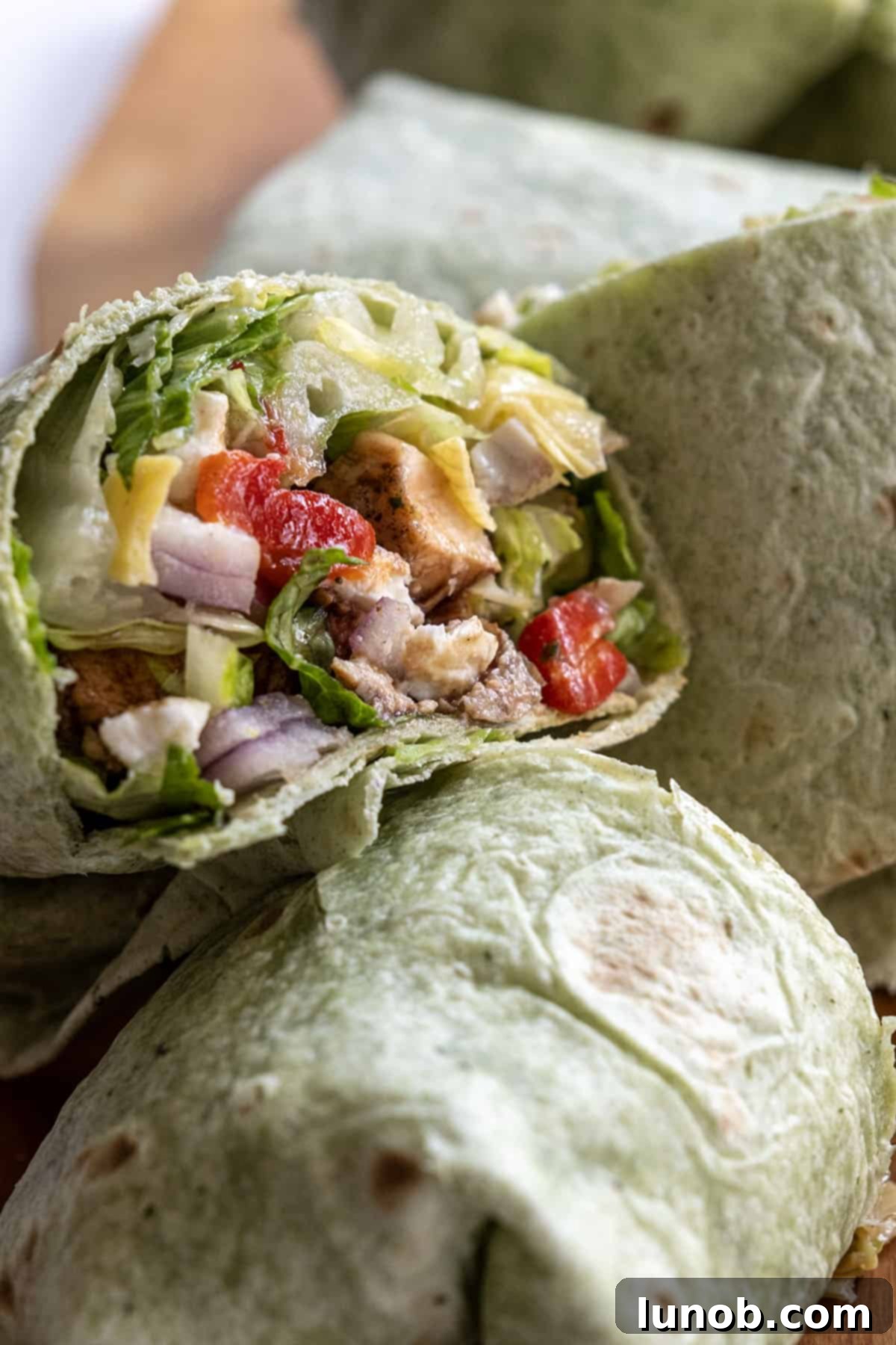 Zesty Mediterranean Chicken Pocket 10 A beautifully rolled Mediterranean chicken wrap, cut in half and showcasing all the vibrant ingredients inside.