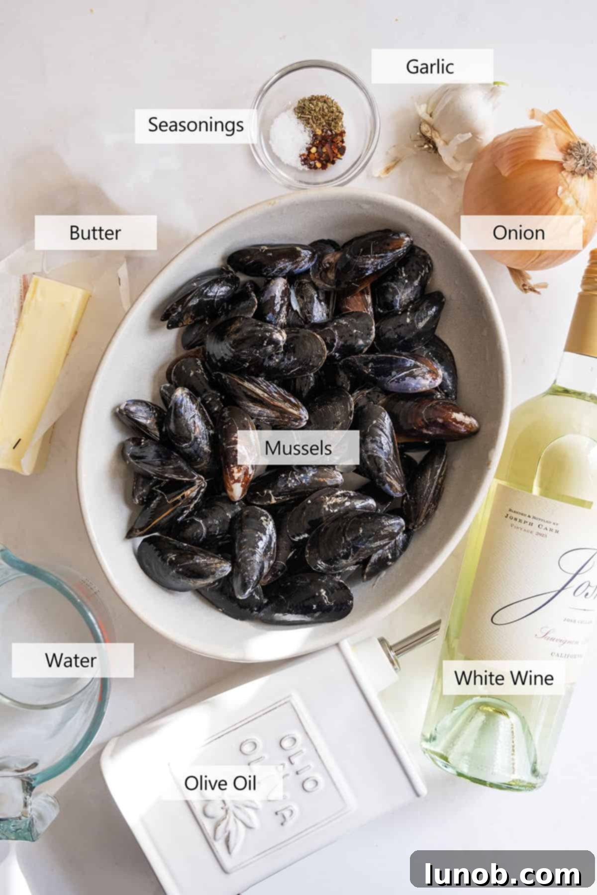 Mussels in Savory White Wine Broth 3 Fresh ingredients laid out for the steamed mussels recipe: shallots, garlic, white wine, mussels, and seasonings.