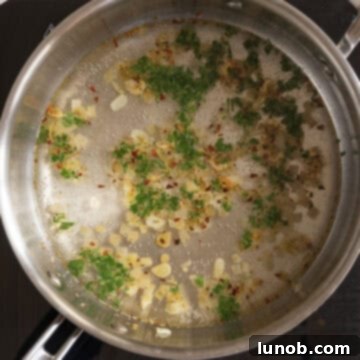 Mussels in Savory White Wine Broth 6 White wine and water simmering in a pan with fresh parsley, creating the flavorful steaming liquid.