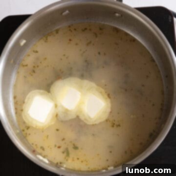 Mussels in Savory White Wine Broth 9 Butter being added to the rich white wine sauce remaining in the pan after the mussels have been removed, creating a smooth finish.