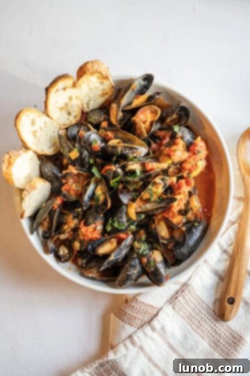 Mussels Fra Diavolo in a large bowl with crusty Italian bread for dipping.