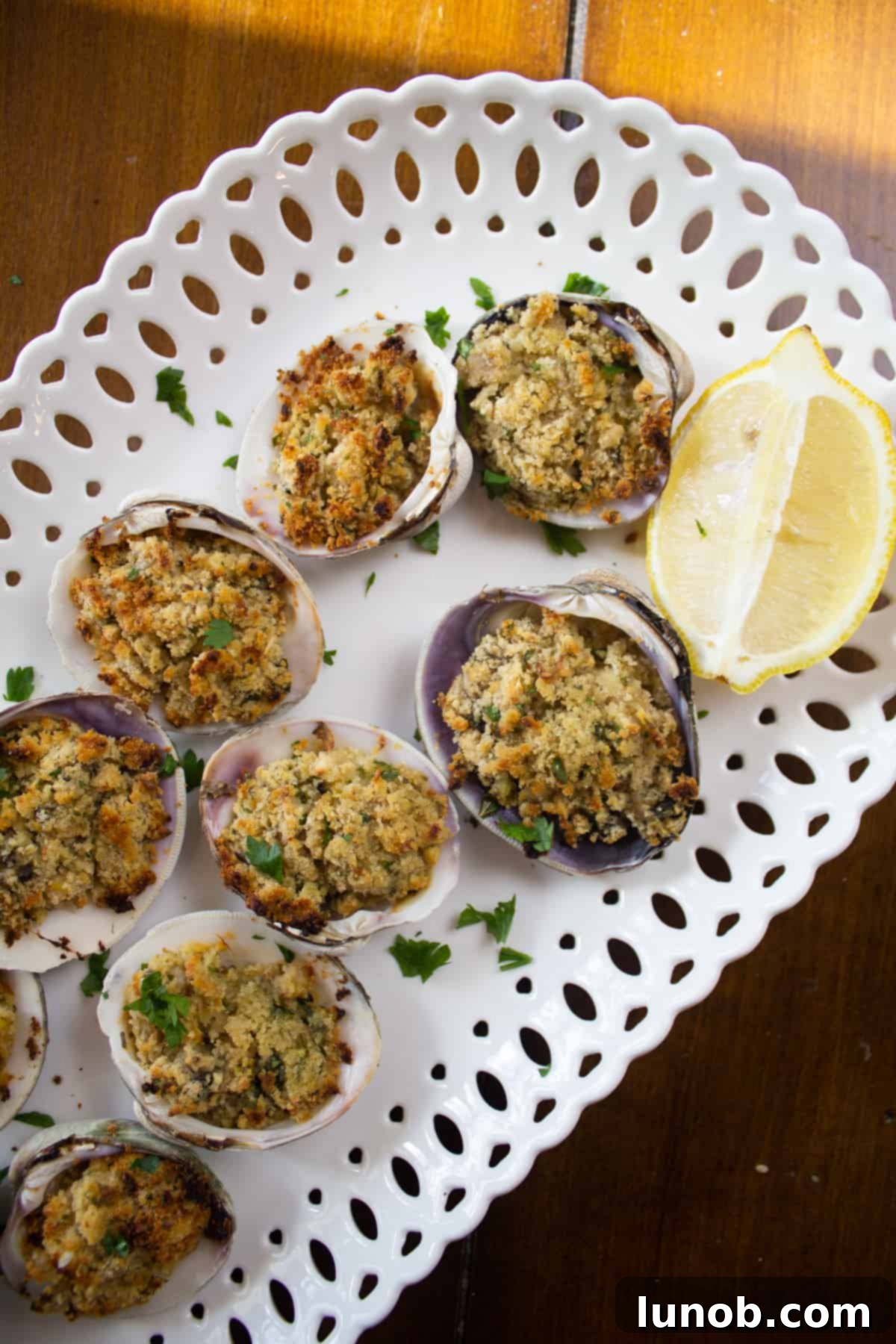 Golden-brown baked clams garnished with fresh lemon wedges.