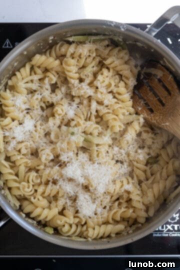 Rustic Sausage and Fennel Pasta 7 Cooked pasta and Parmesan cheese being added to the pan with fennel and sauce.