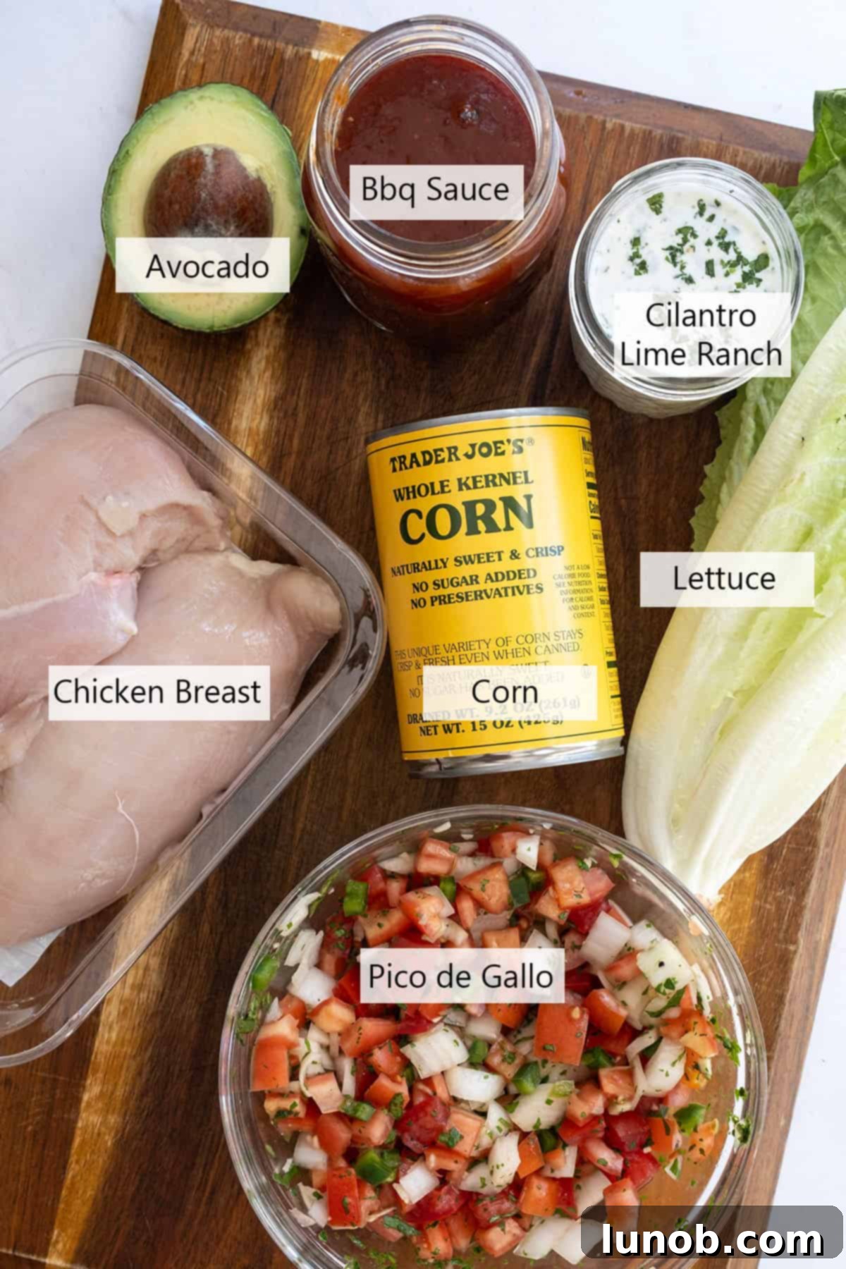 Zesty Chipotle BBQ Chicken Salad 3 Close-up of fresh salad ingredients including vibrant roasted corn, finely chopped pico de gallo, shredded cheese, and creamy avocado slices, ready for assembly.