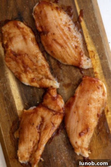 Zesty Chipotle BBQ Chicken Salad 4 Raw chicken breast being expertly brushed with smoky chipotle BBQ sauce for marination before grilling