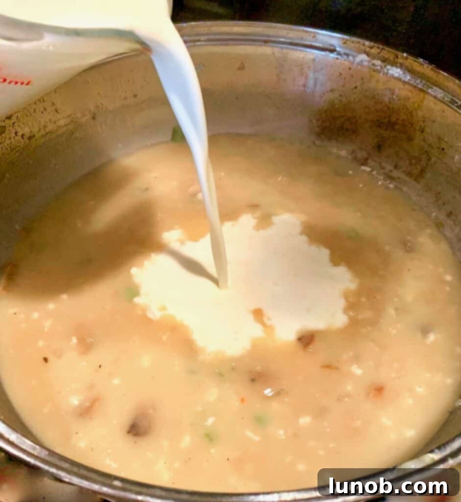 Turkey Tetrazzini: Cheesy Italian Delight with Crispy Garlic Butter Topping 11 Adding heavy cream to the Tetrazzini sauce