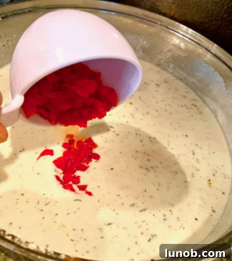 Turkey Tetrazzini: Cheesy Italian Delight with Crispy Garlic Butter Topping 14 Adding chopped pimentos to the Tetrazzini sauce mixture