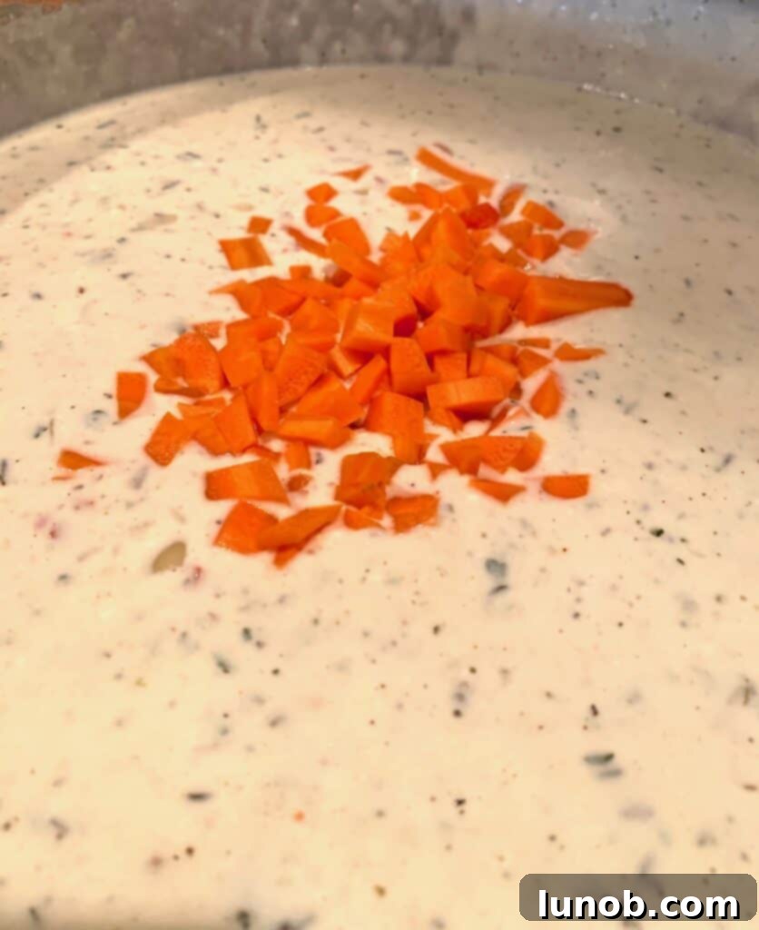 Turkey Tetrazzini: Cheesy Italian Delight with Crispy Garlic Butter Topping 15 Adding chopped carrots to the creamy Tetrazzini sauce