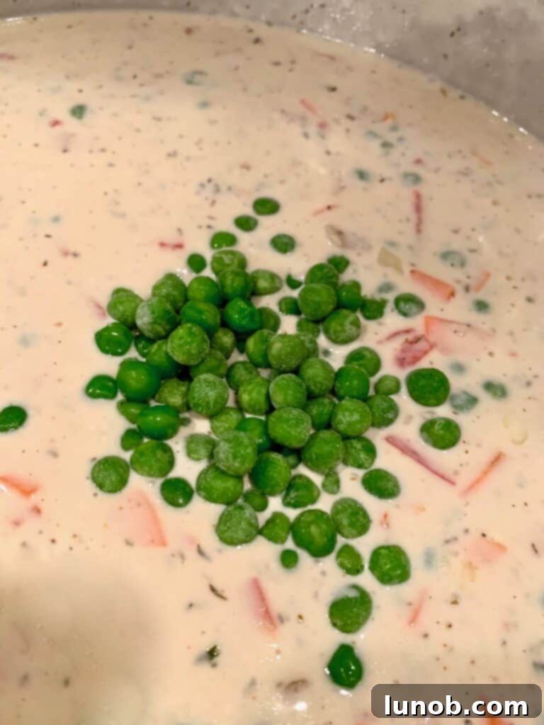 Turkey Tetrazzini: Cheesy Italian Delight with Crispy Garlic Butter Topping 16 Adding frozen peas to the Tetrazzini sauce and vegetables