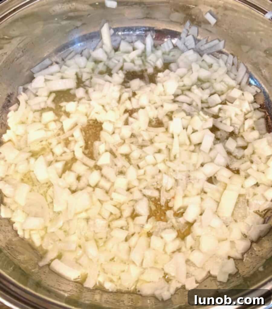 Turkey Tetrazzini: Cheesy Italian Delight with Crispy Garlic Butter Topping 3 Sautéing chopped yellow onions in butter for Turkey Tetrazzini