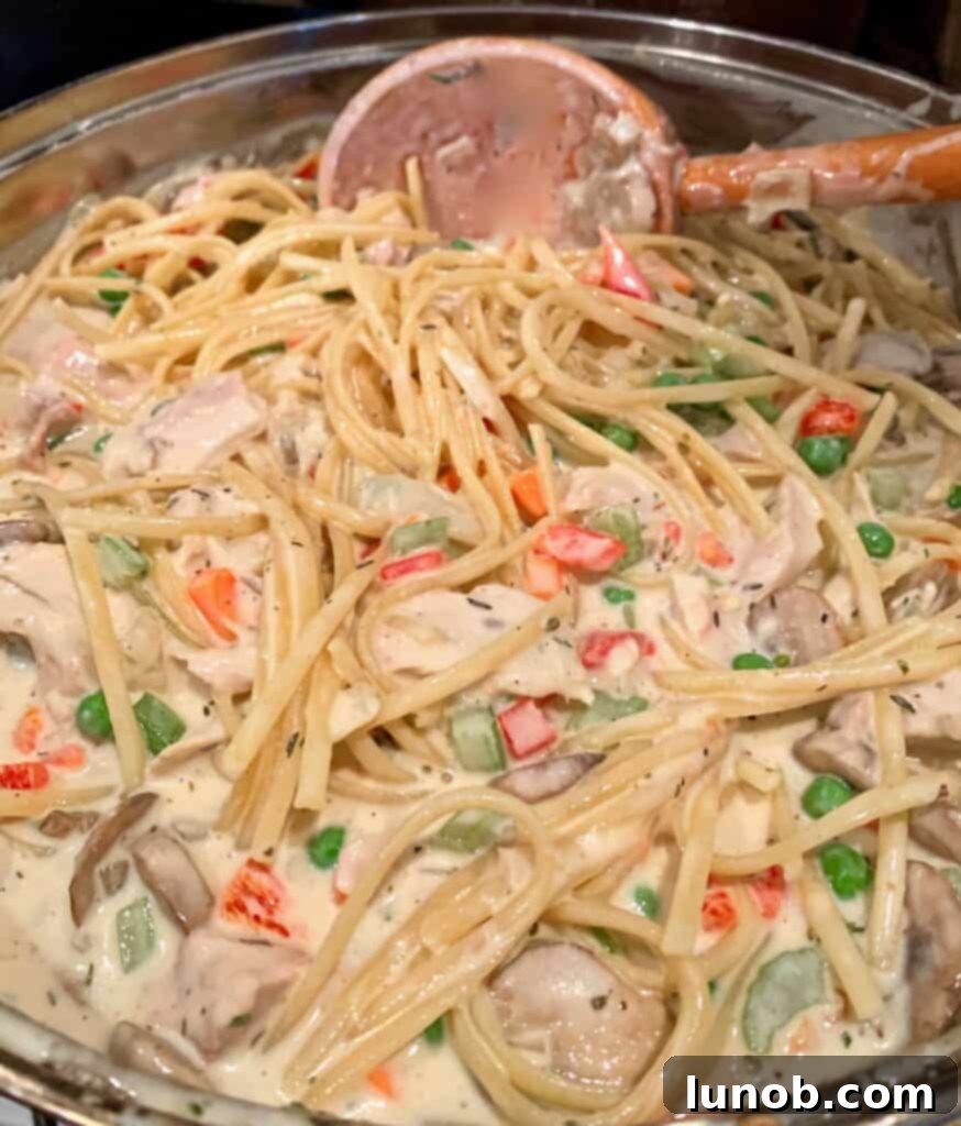 Turkey Tetrazzini: Cheesy Italian Delight with Crispy Garlic Butter Topping 21 Adding partially cooked pasta to the Turkey Tetrazzini sauce and filling