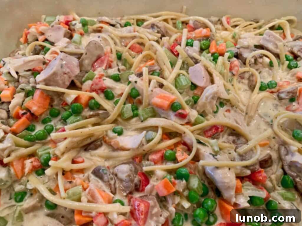 Turkey Tetrazzini: Cheesy Italian Delight with Crispy Garlic Butter Topping 22 Spreading the Turkey Tetrazzini mixture evenly in a casserole dish