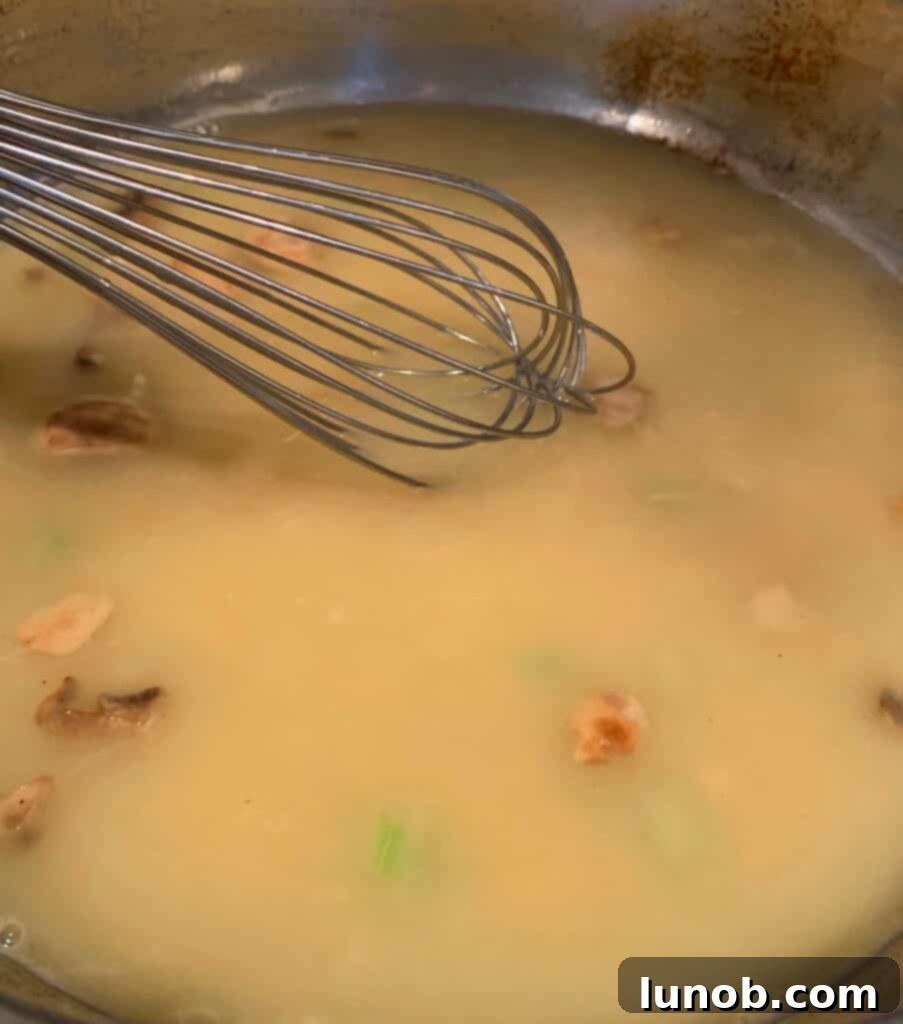 Turkey Tetrazzini: Cheesy Italian Delight with Crispy Garlic Butter Topping 10 Whisking chicken broth into the roux to create a smooth sauce base