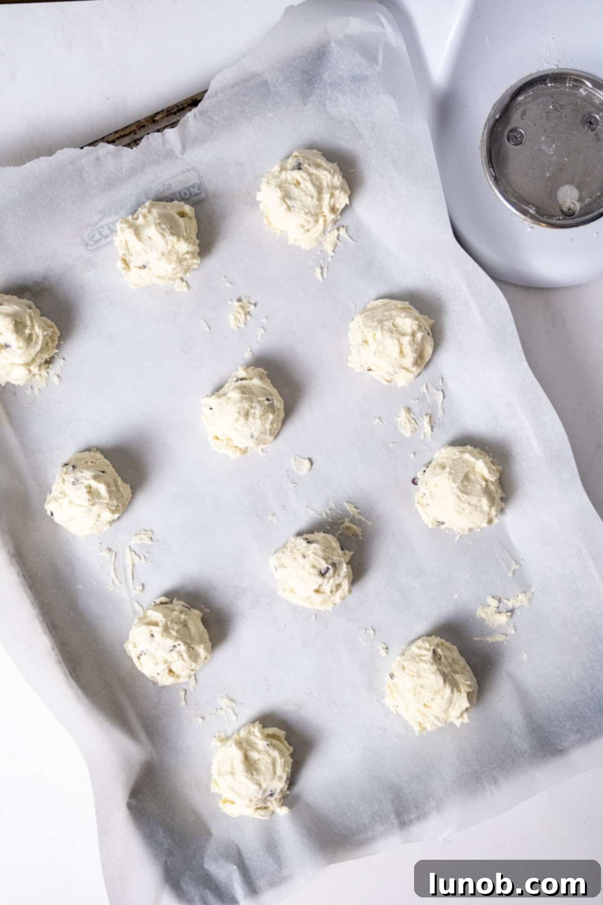 Cookie dough balls neatly arranged on a parchment paper-lined baking tray, ready for baking.