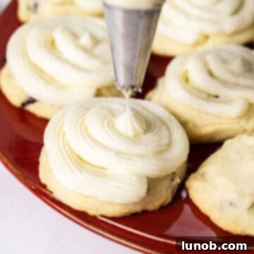 Cookies being frosted with a piping bag, creating decorative swirls on top of the shortbread.