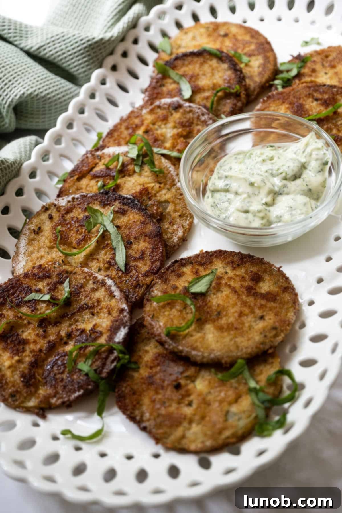 Crispy Italian Fried Green Tomatoes with a side of creamy garlic basil aioli, garnished with fresh basil.