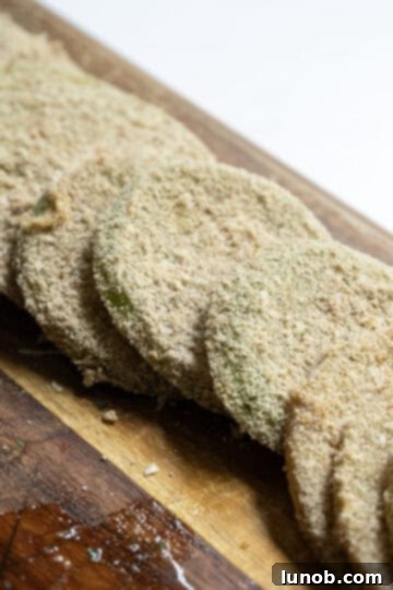 Sliced green tomatoes coated in a flavorful breading, ready for frying.