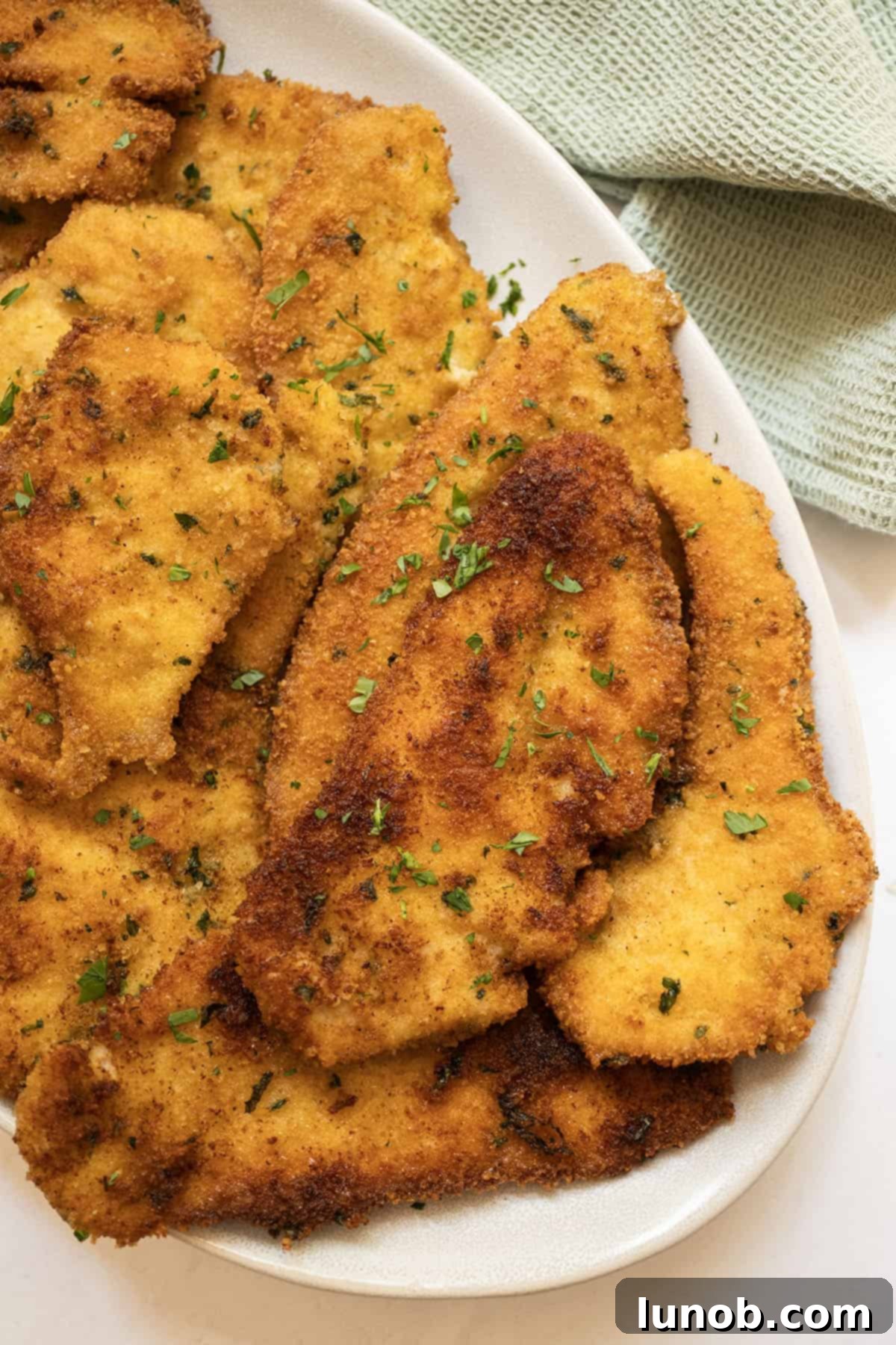 Italian chicken cutlets piled on a plate, golden brown and crispy.