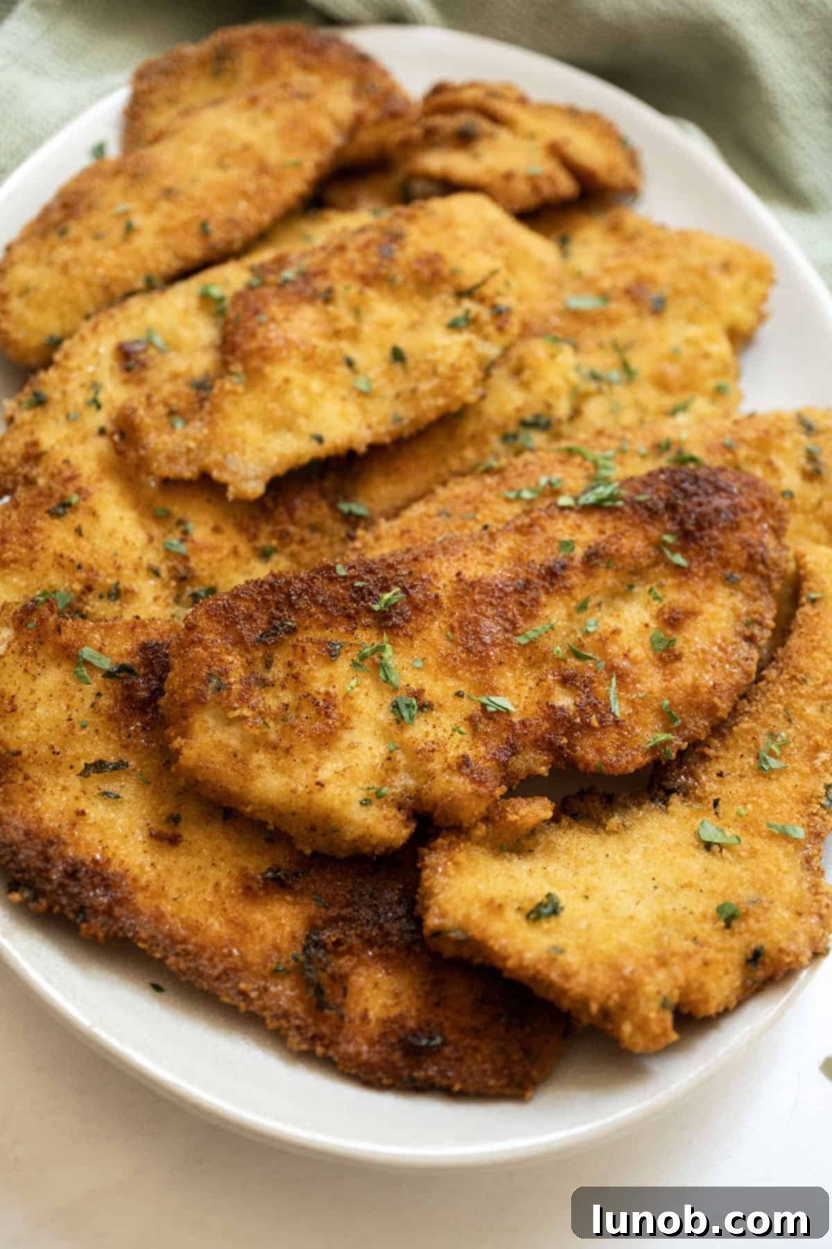 Italian chicken cutlets piled on a plate, ready to be served.